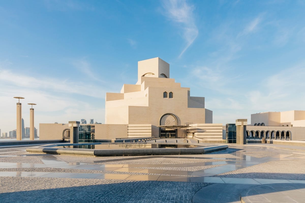Der kubische Kalkstein-Bau des Museum of Islamic Art in Doha mit vorgelagertem Wasserbecken, dahinter die Wolkenkratzer der West Bay
