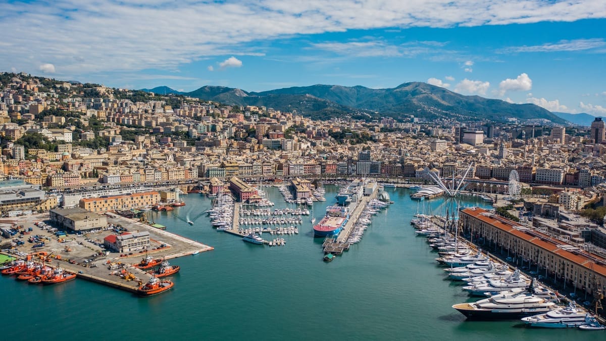 Luftbild des Porto Antico in Genua mit Yachthafen, Riesenrad und der Stadt, die sich hinter dem Hafen die Hügel hinaufzieht
