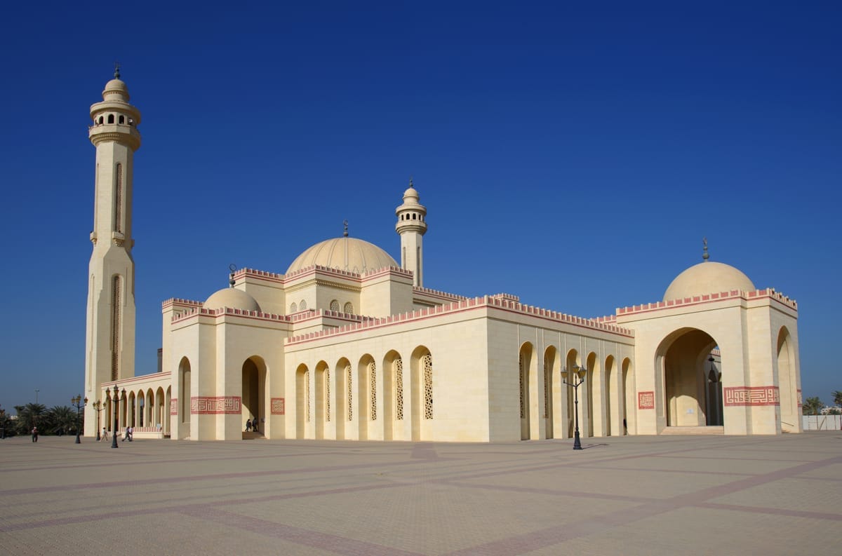 Die Al-Fateh-Moschee in Manama mit heller Sandsteinfassade, zwei Minaretten und großer Kuppel unter wolkenlosem Himmel