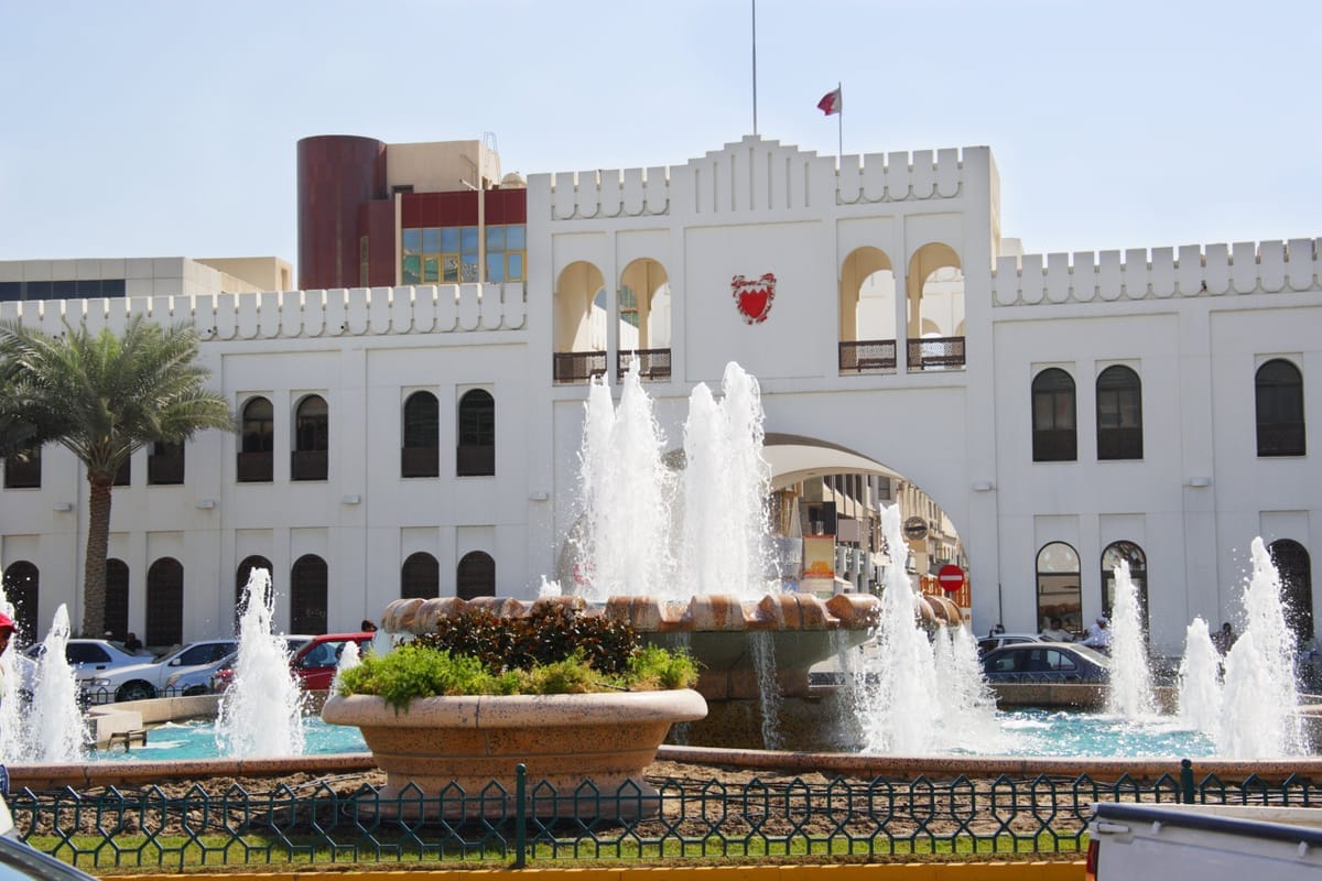 Das weiße Torgebäude Bab el-Bahrain mit Bogendurchgang und Staatswappen, davor ein Springbrunnen auf dem Vorplatz