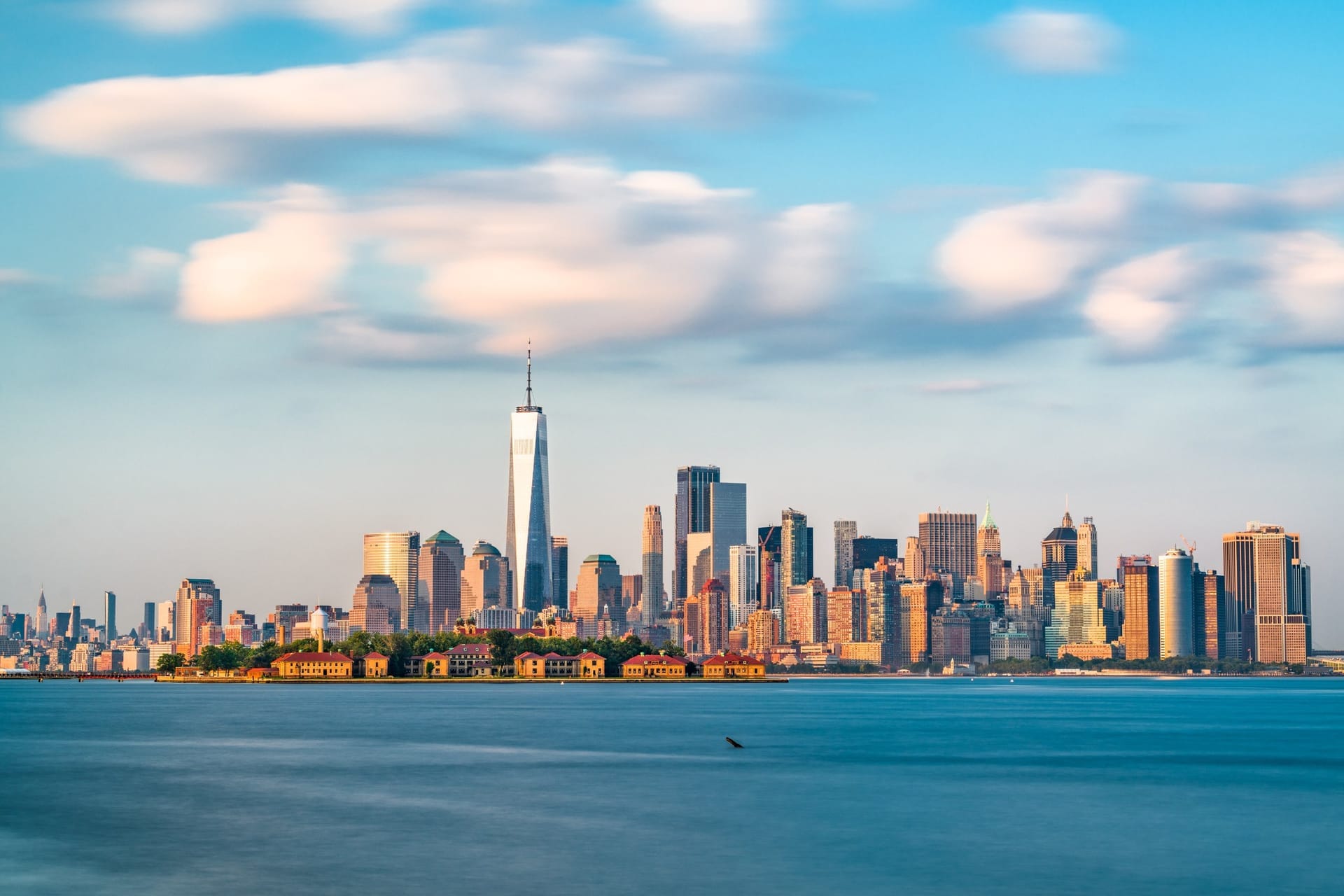 Skyline von Lower Manhattan mit One World Trade Center und Ellis Island vom Wasser aus