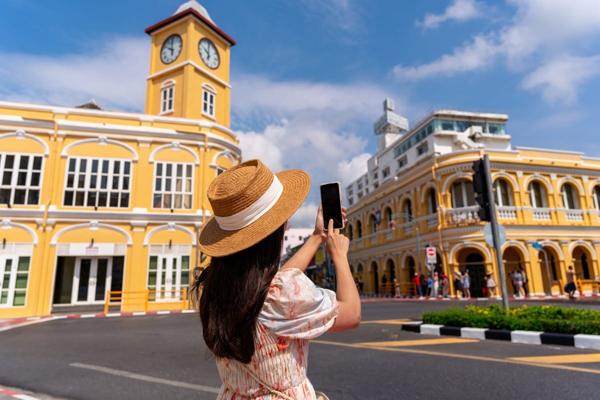 Reisende fotografiert die gelben Shophaus-Fassaden in der Altstadt von Phuket bei Sonnenschein