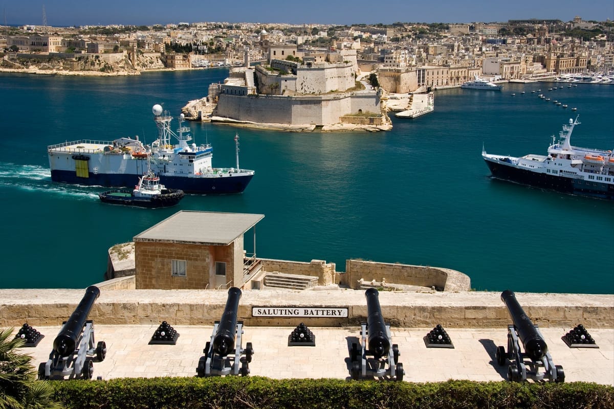 Die Kanonenreihe der Saluting Battery unterhalb der Upper Barrakka Gardens, dahinter der Grand Harbour mit Fort St. Angelo und den Three Cities