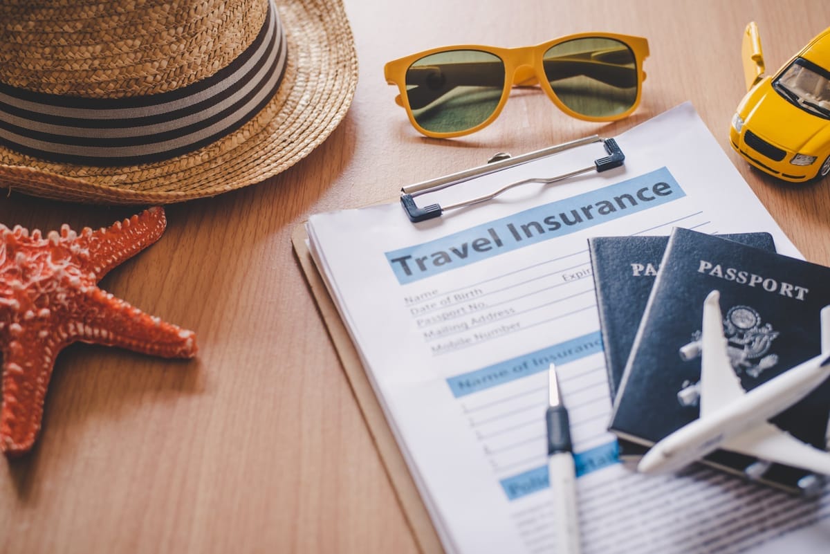 Reiseversicherungsformular mit Reisepässen, Sonnenbrille, Strohhut und Spielzeugauto auf einem Tisch