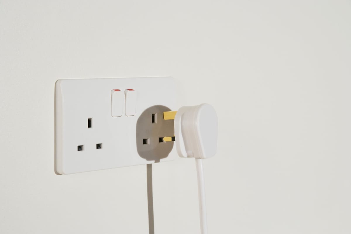 Weißer Netzstecker in einer Wandsteckdose mit zwei Schaltern