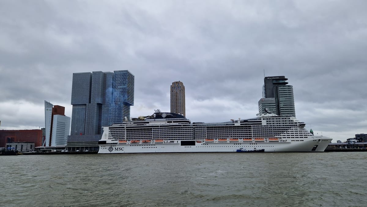 Die MSC Virtuosa liegt am Kai in Rotterdam, dahinter die Hochhäuser der Kop van Zuid
