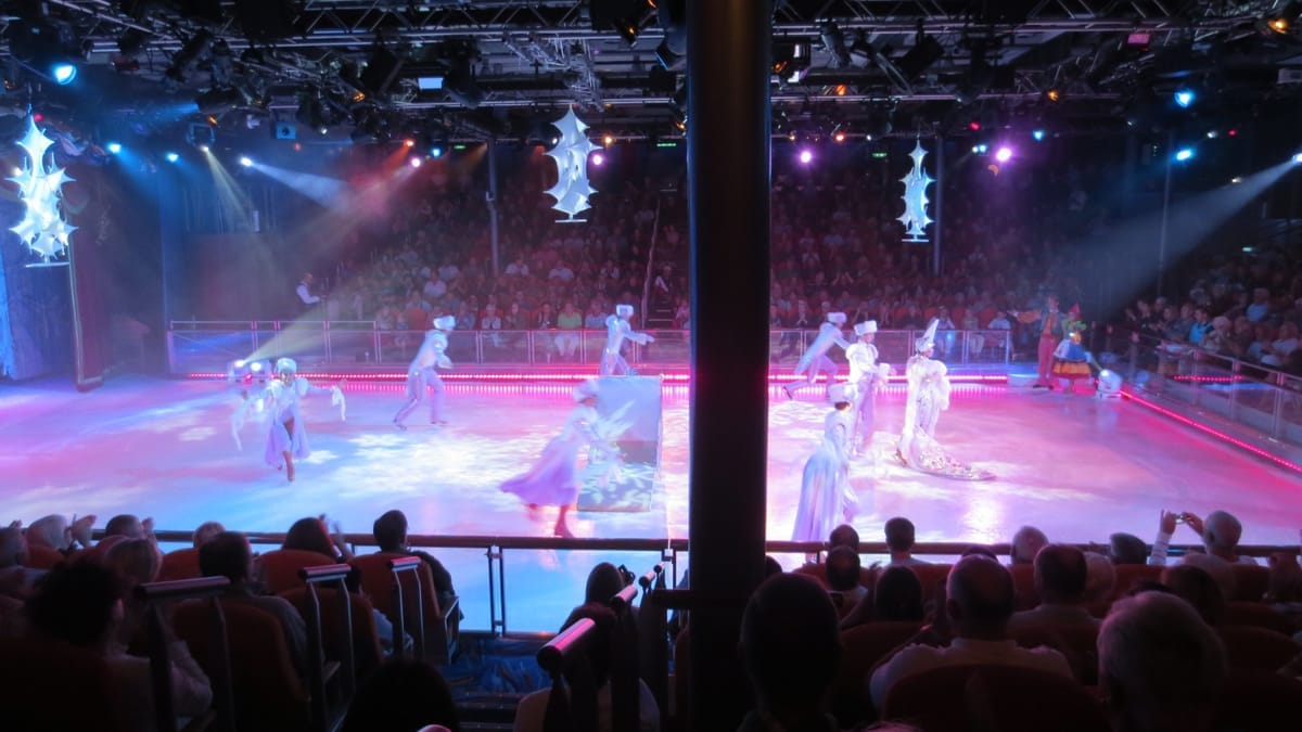 Eisshow in einem vollbesetzten Bordtheater, Tänzerinnen in weißen Kostümen auf der Eisfläche